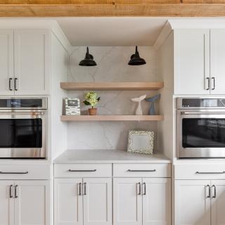 Modern kitchen with white cabinetry, stainless steel appliances, and wooden shelves.
