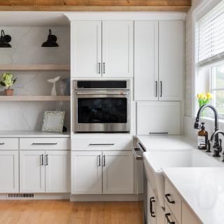 Modern kitchen with white cabinets, stainless appliances, and a wooden beam accent.