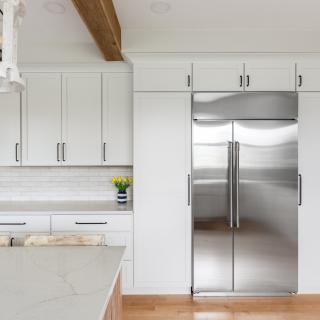 Modern kitchen with white cabinets, stainless steel fridge, and a flowering vase.