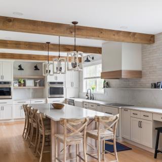Modern kitchen with white cabinetry, wood beams, and a spacious island with seating.