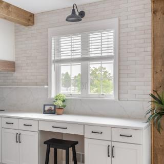 Modern kitchen corner with white cabinets, a marble countertop, and a window view.