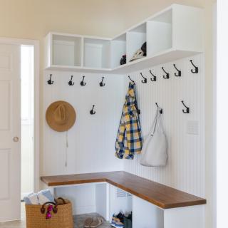 Bright mudroom with hooks, shelves, a wooden bench, and storage baskets.
