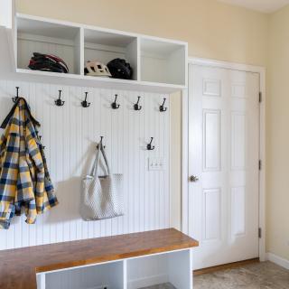 Elegant mudroom with hooks, a bench, and sports equipment storage.