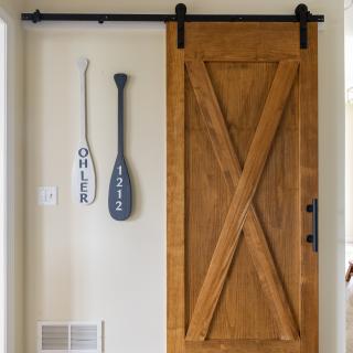 Wooden sliding barn door next to decorative paddles on a wall.