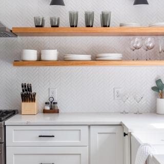 Modern kitchen with open shelving, displaying glassware and dishes above a white countertop.