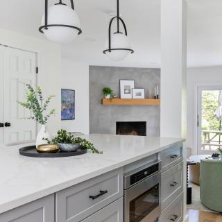 Modern kitchen featuring gray cabinets, marble countertop, and stylish pendant lights.