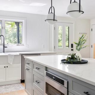 Modern kitchen with white cabinetry, a large sink, and stylish decor elements.